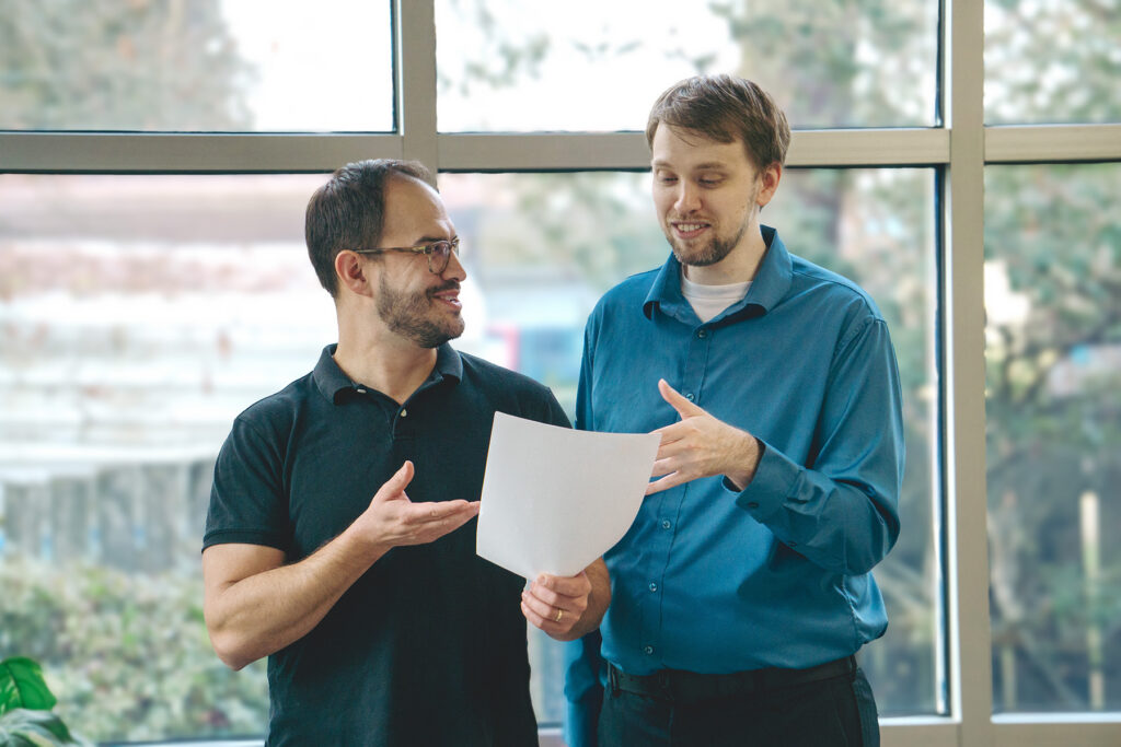 Two smiling professionals collaborating on paperwork in a bright, modern office setting, symbolizing expertise in business software solutions and Managed IT Services for SMBs, including ERP, HR, TLM, and payroll software.