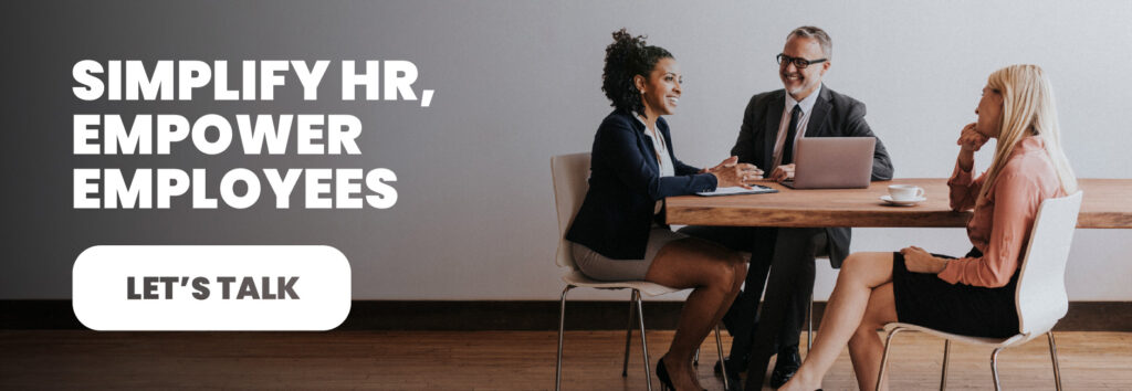 Three professionals in a modern office setting having a collaborative HR discussion around a wooden table, representing Bennett/Porter&rsquo;s commitment to simplifying HR and empowering employees through intuitive HCM software solutions tailored for Pacific Northwest businesses.